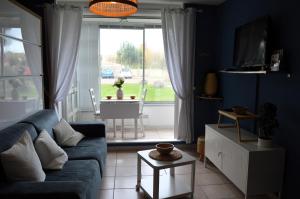 sala de estar con sofá y ventana grande en Le Petit Matelot, studio fonctionnel avec loggia en Courseulles-sur-Mer