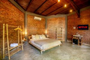 a bedroom with a bed and a brick wall at Pachamama Canggu Bali in Canggu