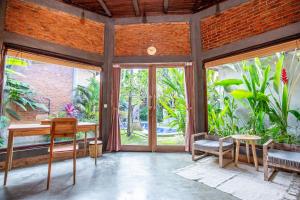 Pokój ze stołem i krzesłami oraz dużymi oknami w obiekcie Pachamama Canggu Bali w mieście Canggu