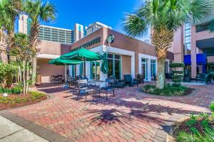 eine Terrasse mit Stühlen und Sonnenschirmen vor einem Gebäude in der Unterkunft Savoy Penthouse 601 in Myrtle Beach