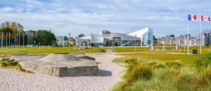 een speeltuin in een park met een gebouw en een vlag bij Le Petit Matelot, studio fonctionnel avec loggia in Courseulles-sur-Mer