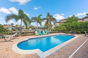 マルコ・アイランドにあるPet-friendly two-story home with pool, spa, and grillのハンモックと椅子、木々が備わるスイミングプール