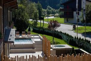 um quintal com uma piscina com cadeiras e uma cerca em Blu Hotel Acquaseria em Ponte di Legno