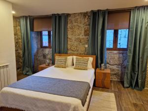 1 dormitorio con 1 cama grande y cortinas verdes en Quinta da Casa dos Santos - Inside Gerês, en Gerês