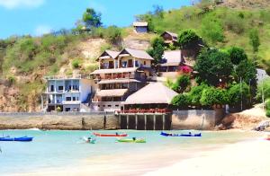 a building on the beach with boats in the water at Surf Garden Lombok in Bumbang