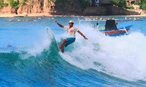 un hombre montando una ola en una tabla de surf en el océano en Surf Garden Lombok, en Bumbang