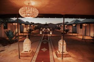 un complexe avec des lumières, des tables et des parasols dans l'établissement Moonlight Desert Camp, à Merzouga