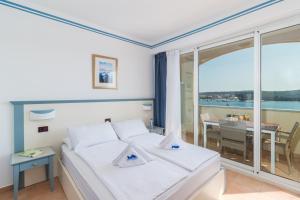 ein Schlafzimmer mit einem Bett und ein Balkon mit einem Tisch in der Unterkunft Family Resort del Mar in Pula
