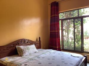 a bedroom with a bed and a large window at Pleasant Rusororo in Kigali