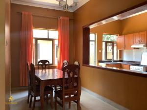 a dining room with a table and a kitchen at Pleasant Rusororo in Kigali