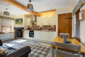 cocina con armarios blancos y mesa de madera en Country Cottage by St. Andrews en St Andrews