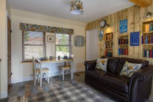 sala de estar con sofá, mesa y escritorio en Country Cottage by St. Andrews, en St Andrews