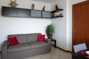 uma sala de estar com um sofá cinzento com duas almofadas vermelhas em Bella Ciao Airport Apartment em Seriate