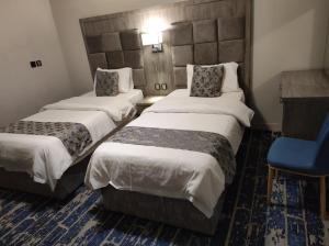 a hotel room with two beds and a blue chair at فندق اجنحة السمو بجازان in Jazan
