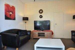 a living room with a black couch and a tv at Het Voorhuis in Grolloo