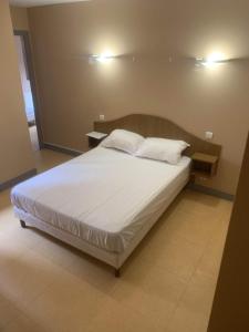 a bed with white sheets and pillows in a room at La Taverne du Boucher in Sarlande