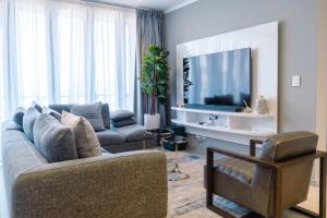 Jordan's Luxe Apartments في جوهانسبرغ: غرفة معيشة بها أريكة وتلفزيون