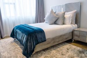 Jordan's Luxe Apartments في جوهانسبرغ: غرفة نوم عليها سرير وبطانية زرقاء