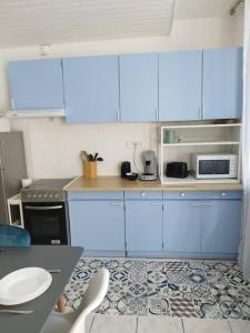 a kitchen with blue cabinets and a table and chairs at Maison atypique avec garage 2 roues - Proche Gare in Le Havre