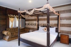 1 dormitorio con cama con dosel y sofá en Kebon Krapyak Cottage Syariah Mitra RedDoorz near Stadion Maguwoharjo en Yogyakarta