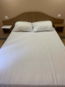 a large white bed with two pillows on it at La Taverne du Boucher in Sarlande