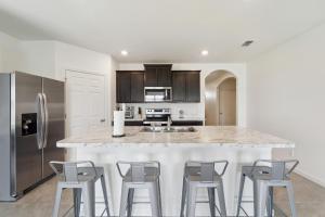 a kitchen with a large island with bar stools at Brand New 4-Bedroom House near Disney & Beaches! in Port Saint Lucie