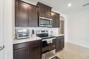 a kitchen with wooden cabinets and a stove top oven at Brand New 4-Bedroom House near Disney & Beaches! in Port Saint Lucie