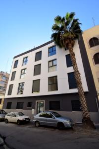 dos coches estacionados frente a un edificio con una palmera en Letmalaga Gazules, en Málaga