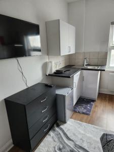 una cucina con armadi bianchi e piano di lavoro nero di Double room in Stone a Kent