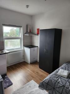 a bedroom with a black cabinet and a window at Double room in Stone in Kent