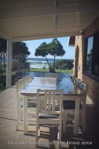 een witte tafel en stoelen op een patio met uitzicht op de oceaan bij Kyalami in Port Edward