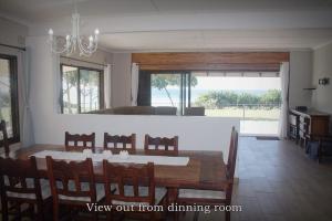 a dining room with a table and chairs and a kitchen at Kyalami in Port Edward