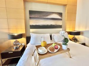 uma bandeja de comida numa cama com bebidas e frutas em Luxury 1 bedroom in Dubai Mall Residences em Dubai