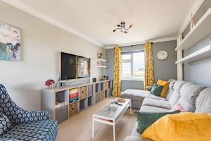 a living room with a couch and a tv at Worth Cottage - Perfect for families & friends in Worth