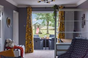 a living room with yellow curtains and a playground at Worth Cottage - Perfect for families & friends in Worth