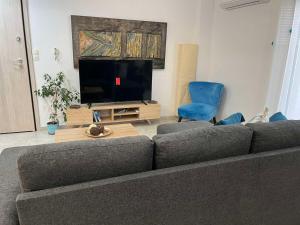 a living room with a couch and a flat screen tv at Blue Siri Apartment in Heraklio