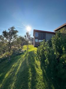 a house in a field with the sun in the sky at Steinsholt - Birta Rentals in Hella