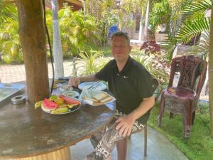 a man sitting at a table with a plate of fruit at Sea View Resort in Kallady