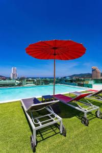 einen Tisch mit einem roten Regenschirm neben einem Pool in der Unterkunft Neon Patong in Patong Beach