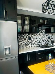 uma cozinha com armários pretos e um frigorífico branco em Elite Escape em Cidade do Cabo