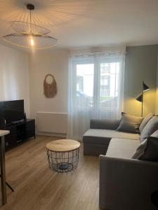 a living room with a couch and a table at Le Cocon Urbain *T2* + Parking in Orléans