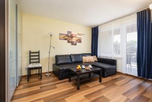 a living room with a black leather couch and a table at Spokojny Apartament blisko Plaży - Spacerowa - by Renters in Łukęcin