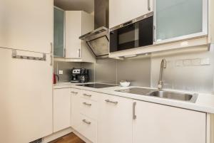 a kitchen with white cabinets and a sink at Spokojny Apartament blisko Plaży - Spacerowa - by Renters in Łukęcin