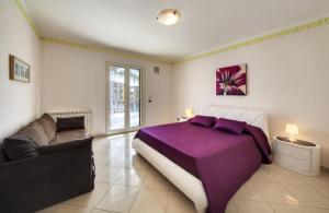 a bedroom with a purple bed and a couch at Villa Magda - private pool 22 pax in Marina di Ragusa +15 photos