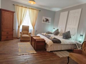 a bedroom with two beds and a chair and a window at Di Plaas Opstal in Fouriesburg