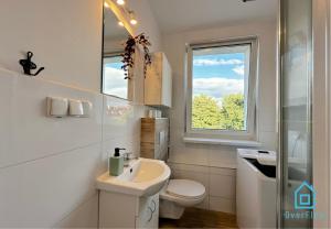 ein Bad mit einem Waschbecken, einem WC und einem Fenster in der Unterkunft August Room in Danzig