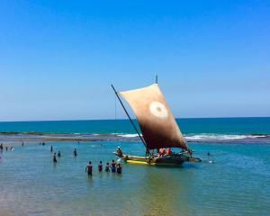 a boat with a sail in the water on a beach at Negombo Morawala Beach Villa in Negombo