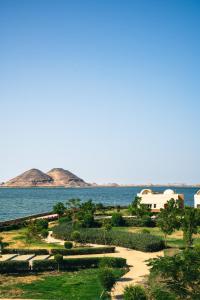a park next to the water with mountains in the background at Azal Lagoons Resort Abu Simbel in Abu Simbel