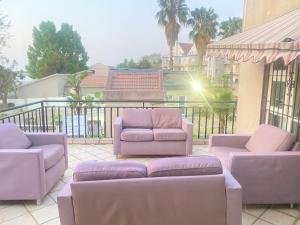 d'une terrasse avec des chaises et des canapés violets sur un balcon. dans l'établissement Siena Sun Guesthouse, à Midrand
