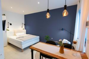 a bedroom with a bed and a table and lights at Goldstadt Apartments in Pforzheim